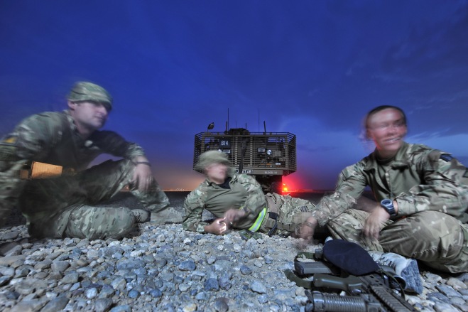 Three soldiers relax at dusk during a break in a Combat Logistic Patrol